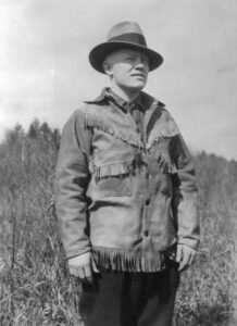Gordon MacQuarrie wearing a fringed buckskin jacket, at Little Bass Lake, WI, 1928.
